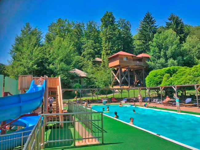 Bild von der Baumhaus Hotel Anlage mit Salzwasserpool und Wasserrutsche im Styrassic Park